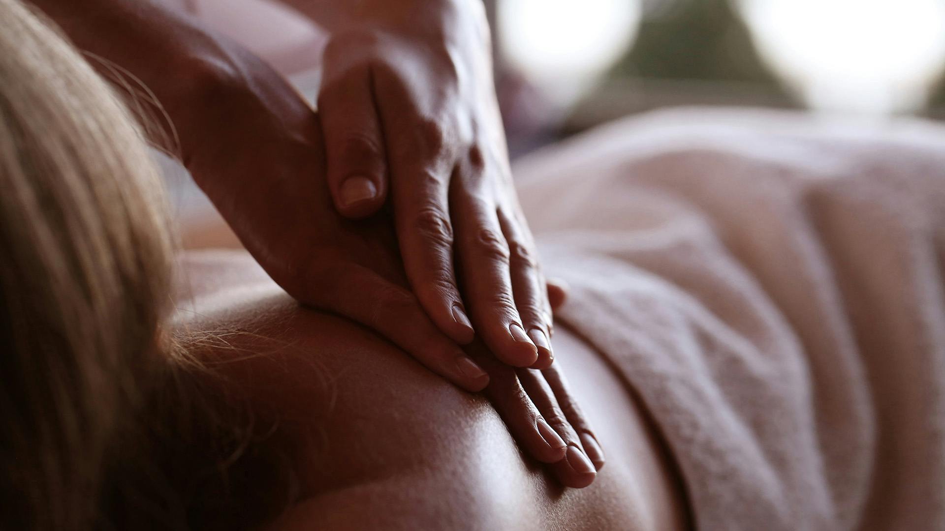 Close-up of hands applying pressure on a back during a massage